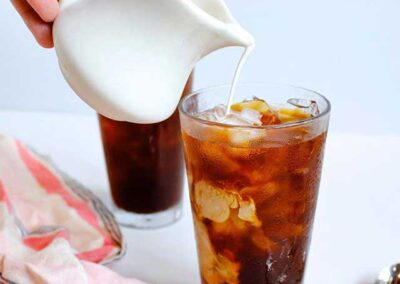 Milk being poured into iced coffee